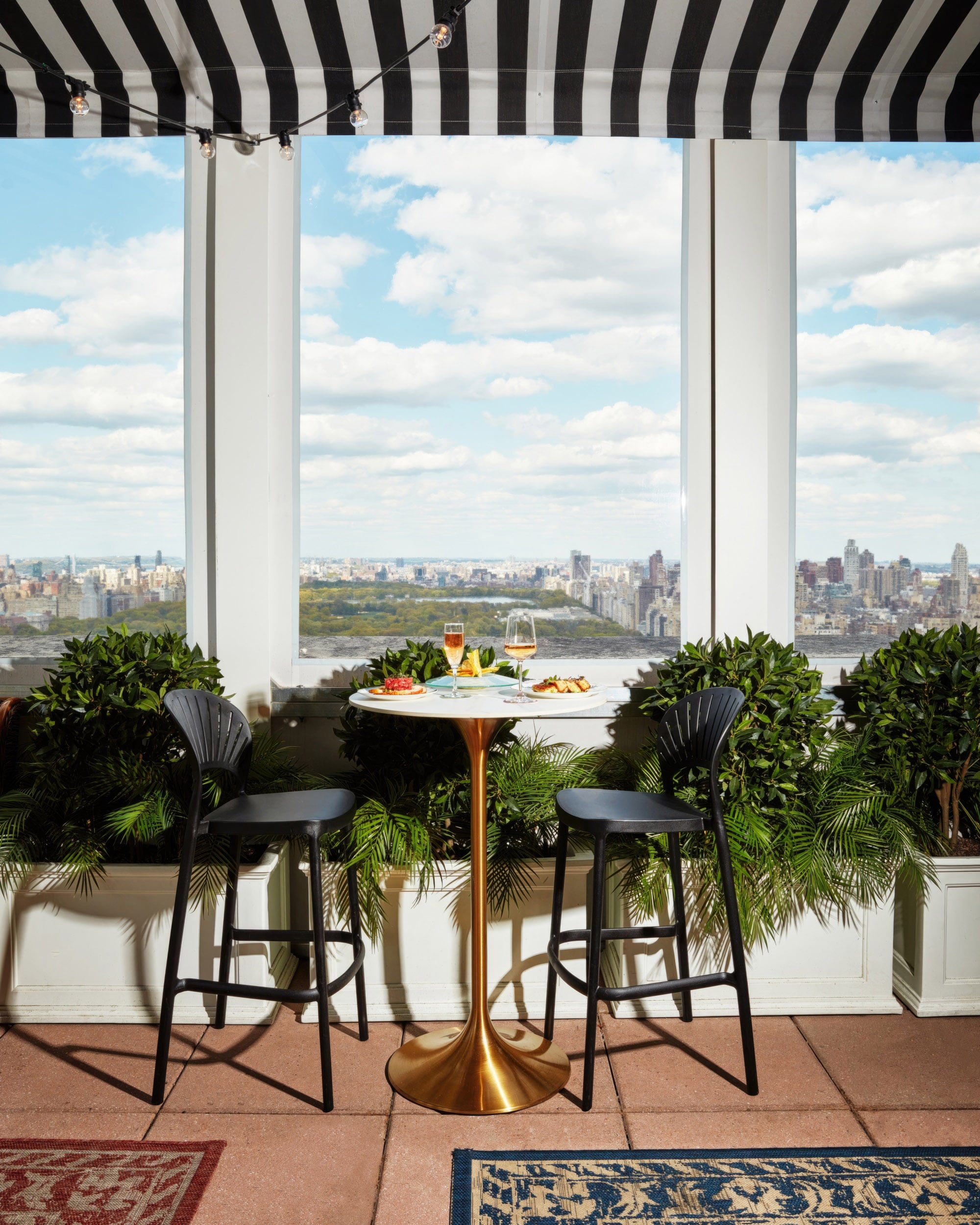 A rooftop bar with a table and chairs overlooking the city.