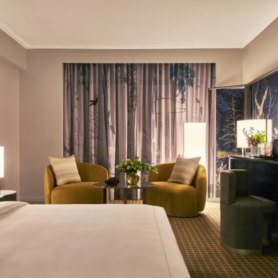 A room with king bed, 2 chairs, a mural and tv in the park lane king room.