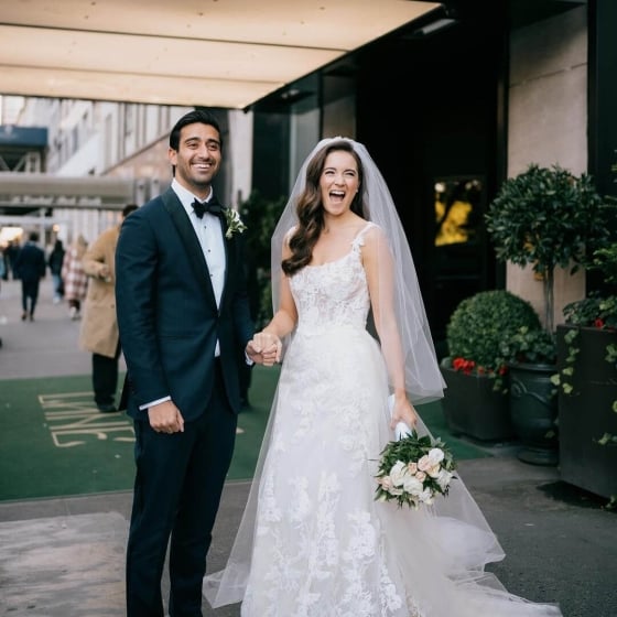 A bride and groom are smiling in front of the entrance of Park Lane.