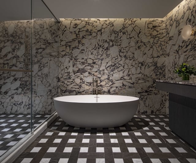 A modern bathroom with a freestanding tub, marble walls, and a checkered floor.