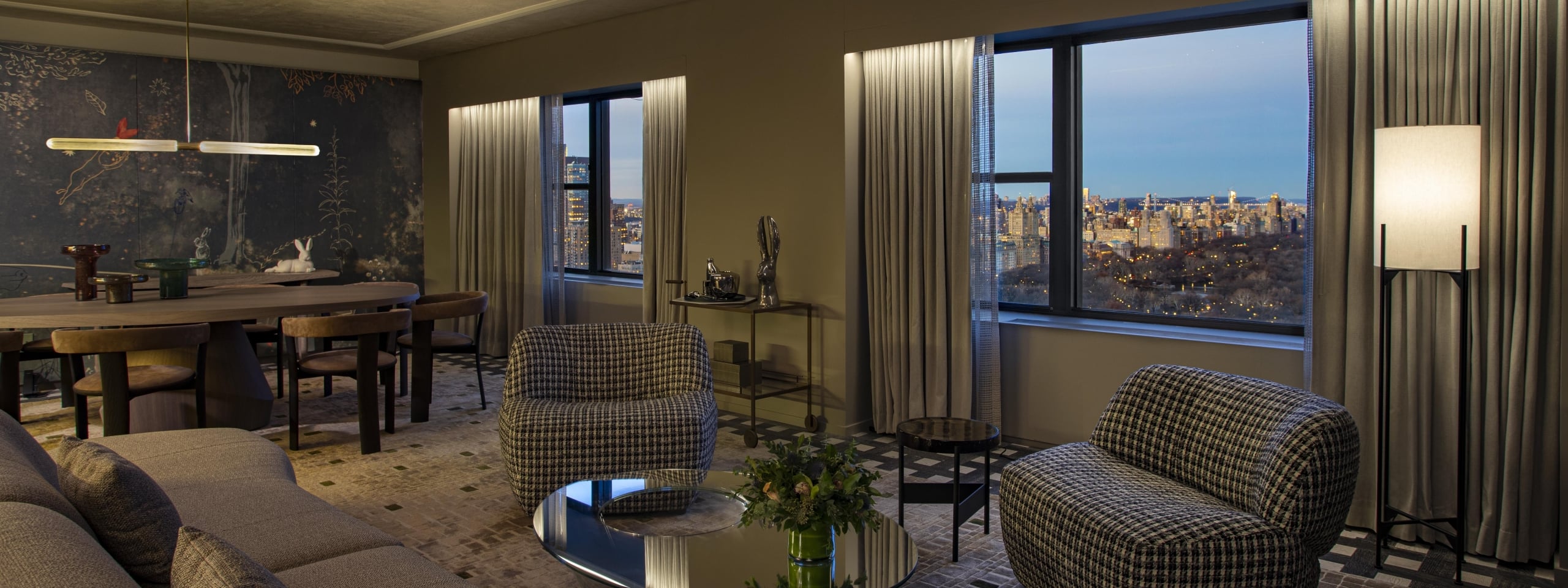 A wide view of a luxurious suite with a dining area, seating area, and city view.