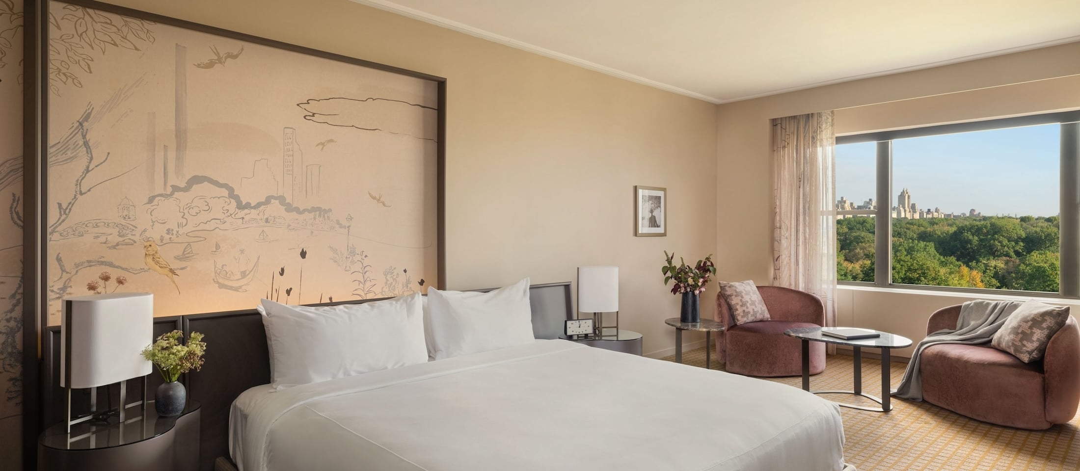 A hotel room with a king-sized bed, sitting area, and city view.