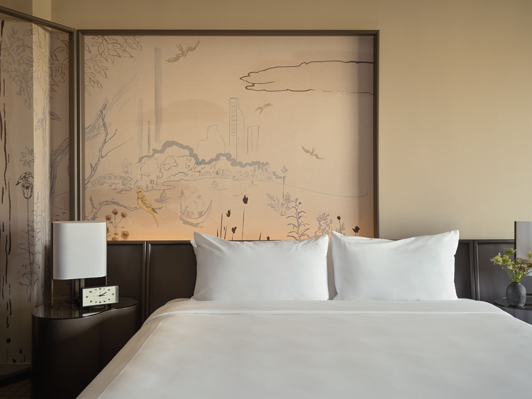 A king bed with side table and painted mural behind.