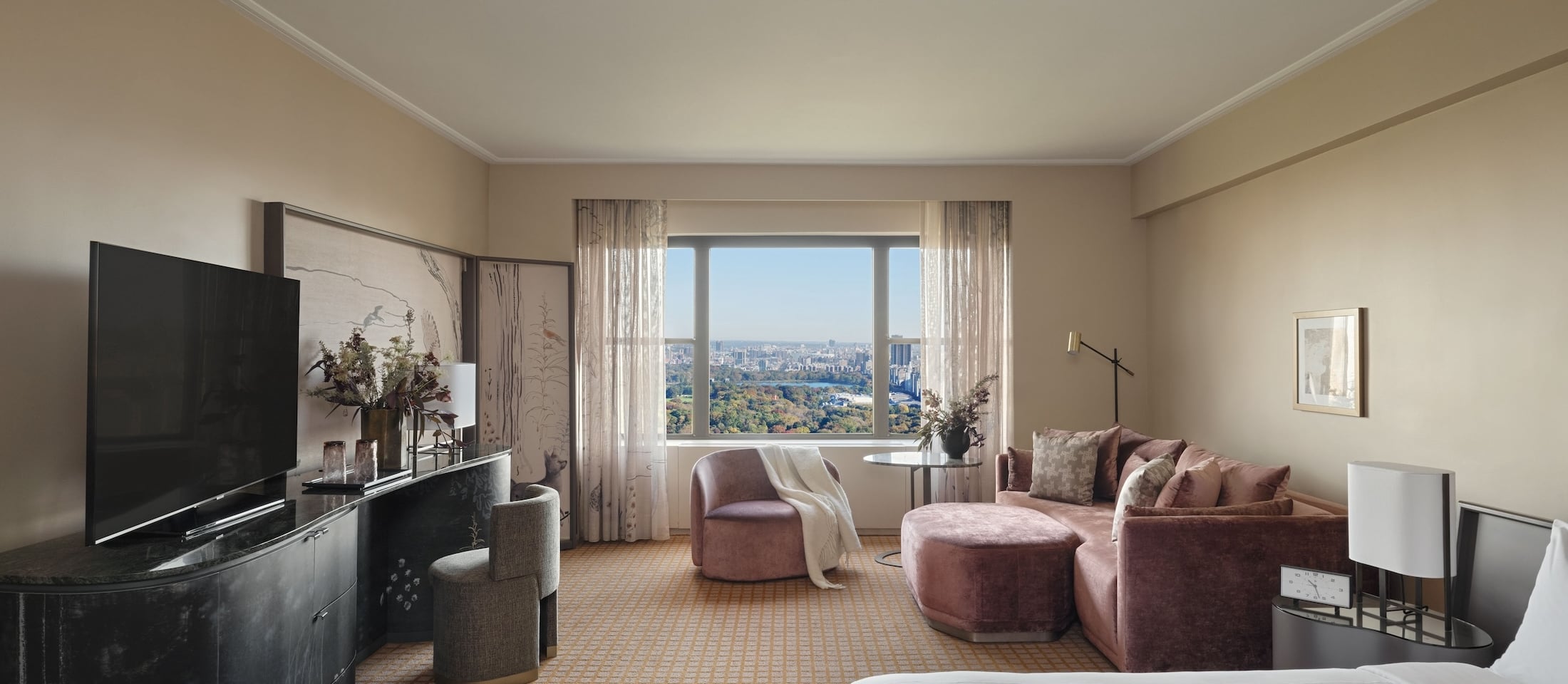 A luxurious hotel room with a sitting area, large window, and city view.
