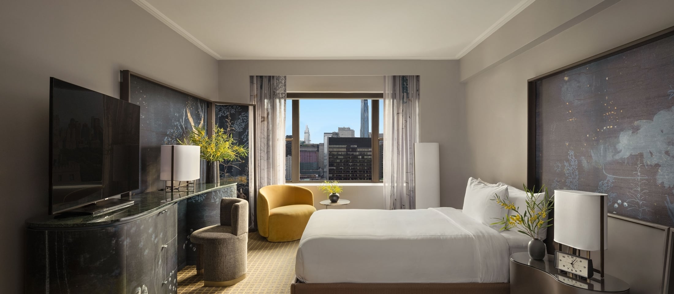 A hotel room with a city view, two queen beds, a large window, a desk, a flat-screen TV, and a chair.