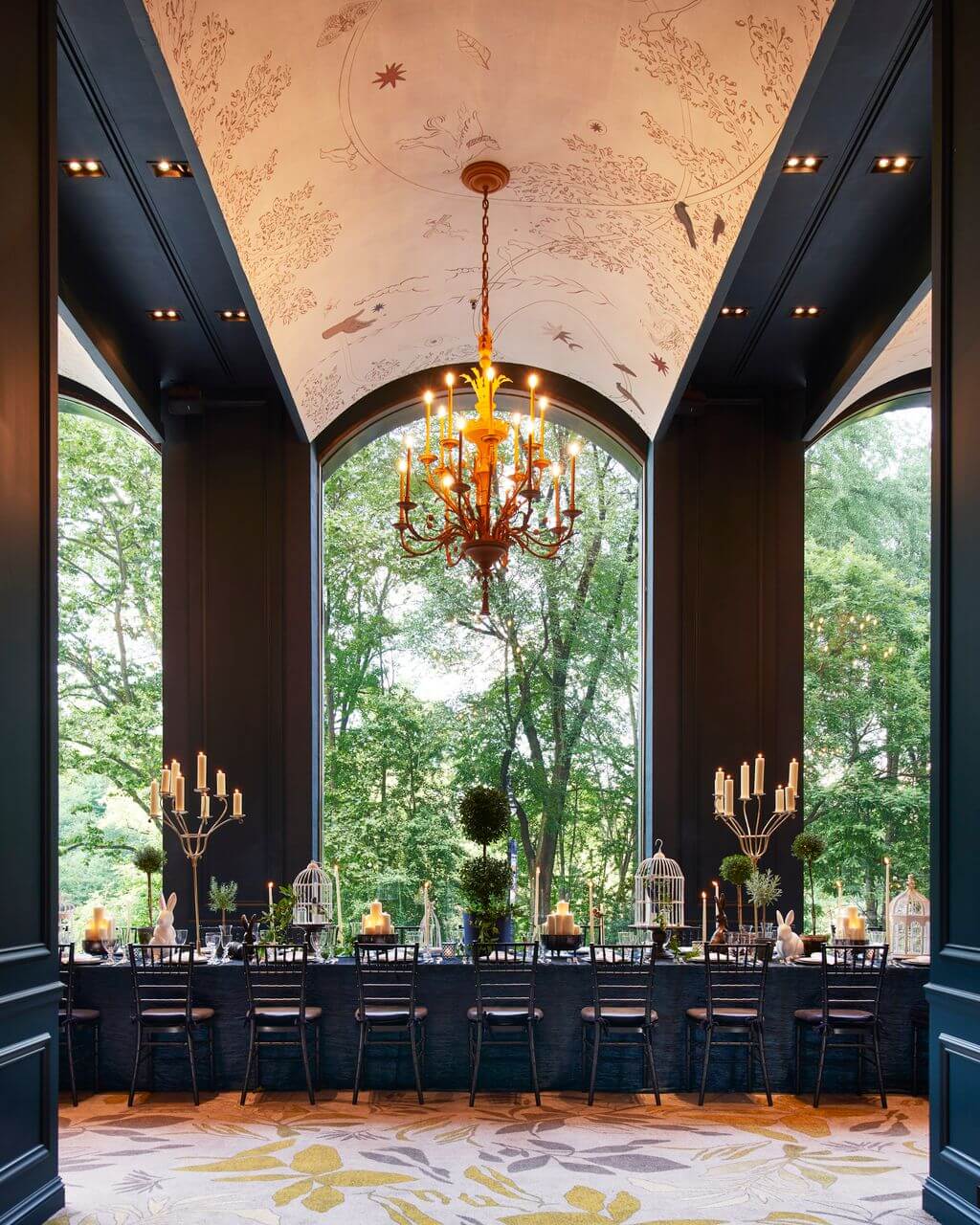 A formal dining room with a large table, chairs, and a chandelier.