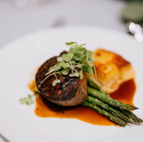 plated dish featuring a cut of filet mignon served with asparagus and potatoes.