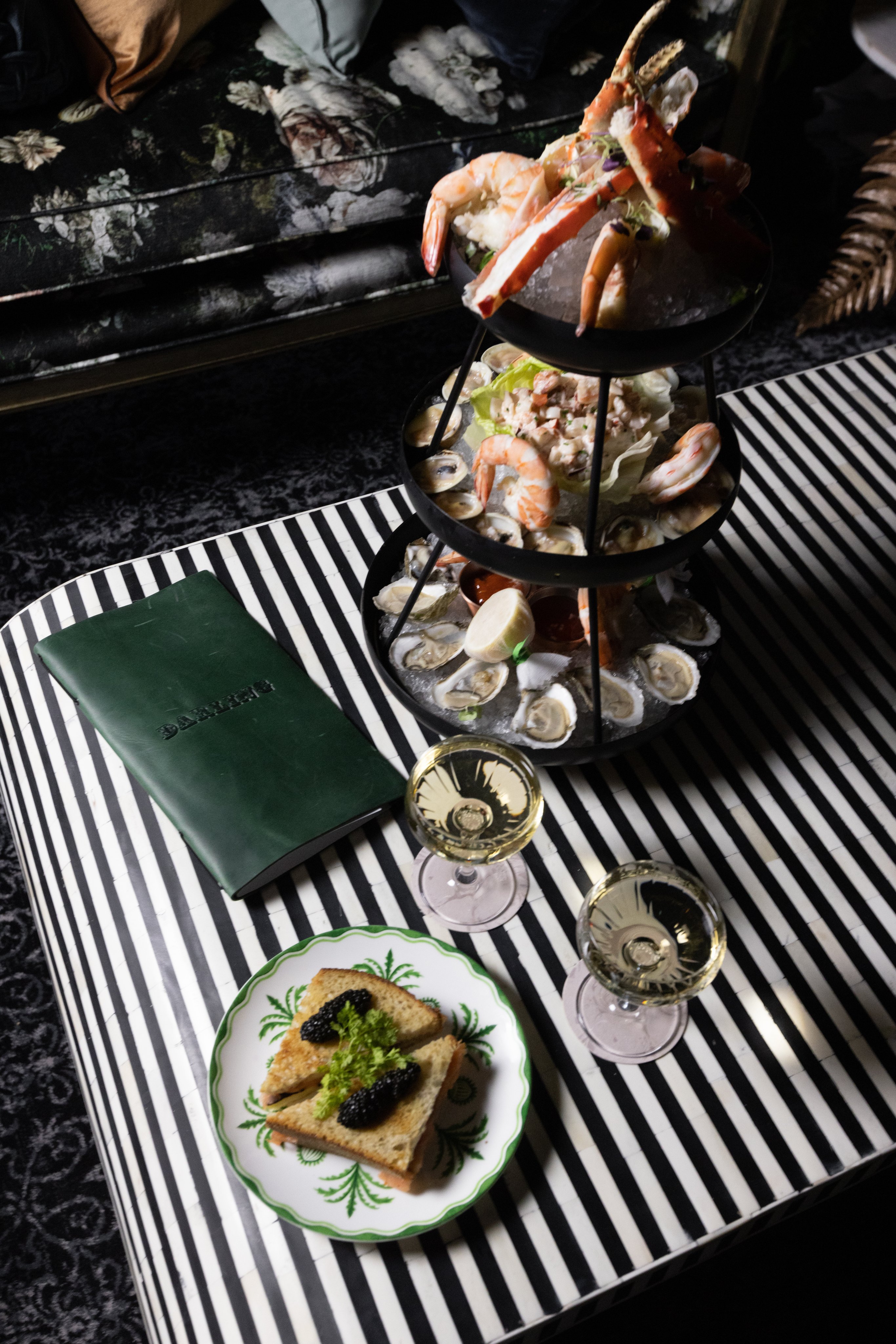 A seafood tower with oysters, shrimp, and crab, accompanied by wine and toast.