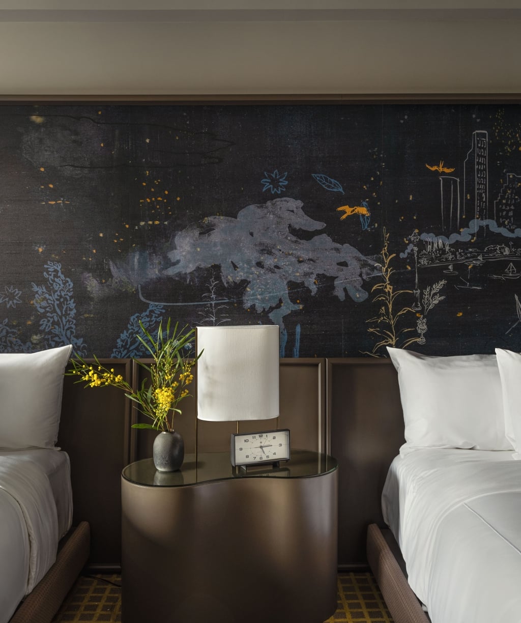 A hotel room with two twin beds, a nightstand, and a large artwork mural behind the beds.