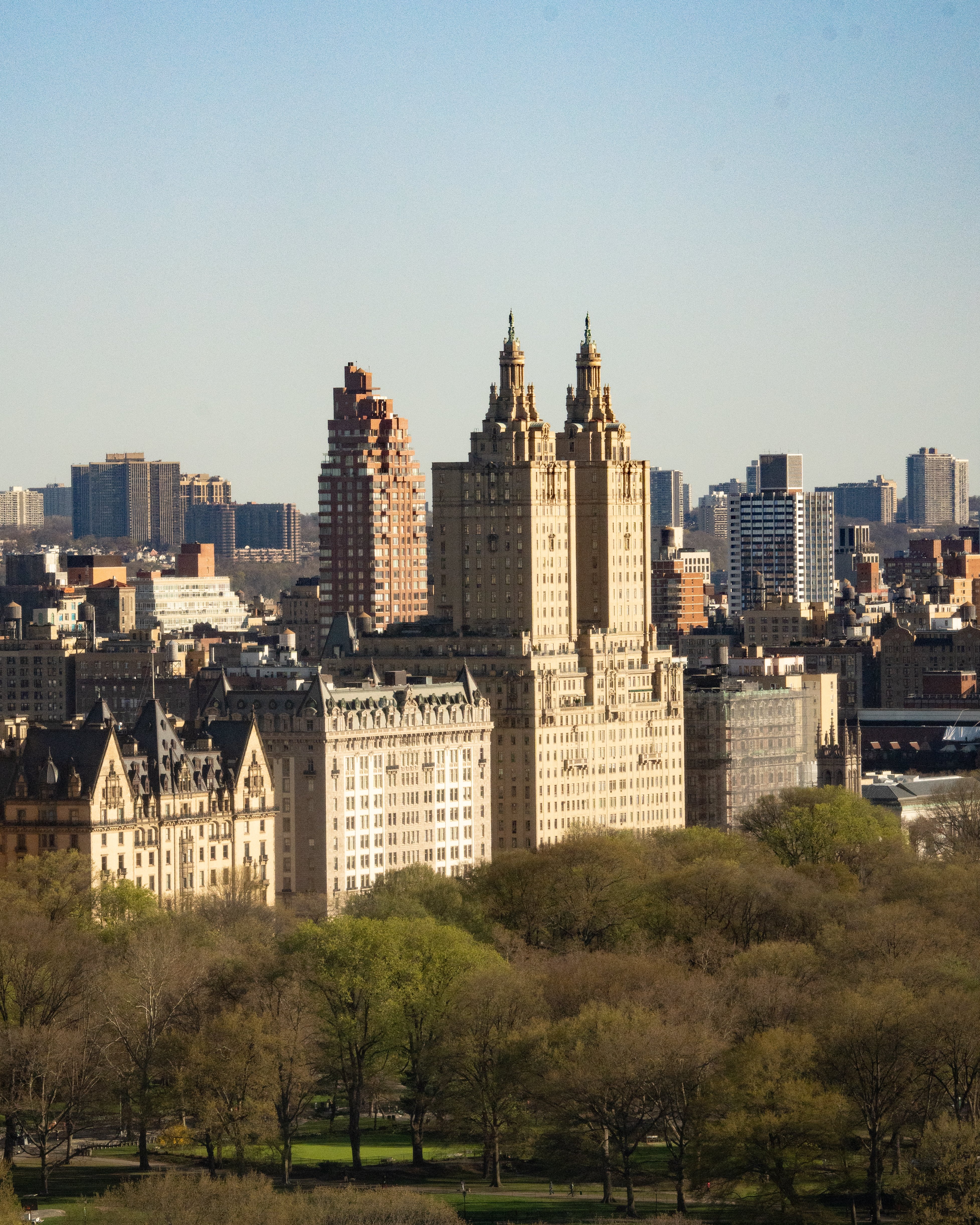 A wide view of a large building complex surrounded by trees and cityscape.